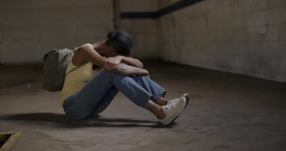 Woman sits on a floor with her head on her arms
