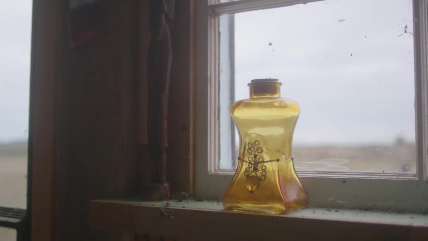 The sun is shining through a window and glass bottle inside a home