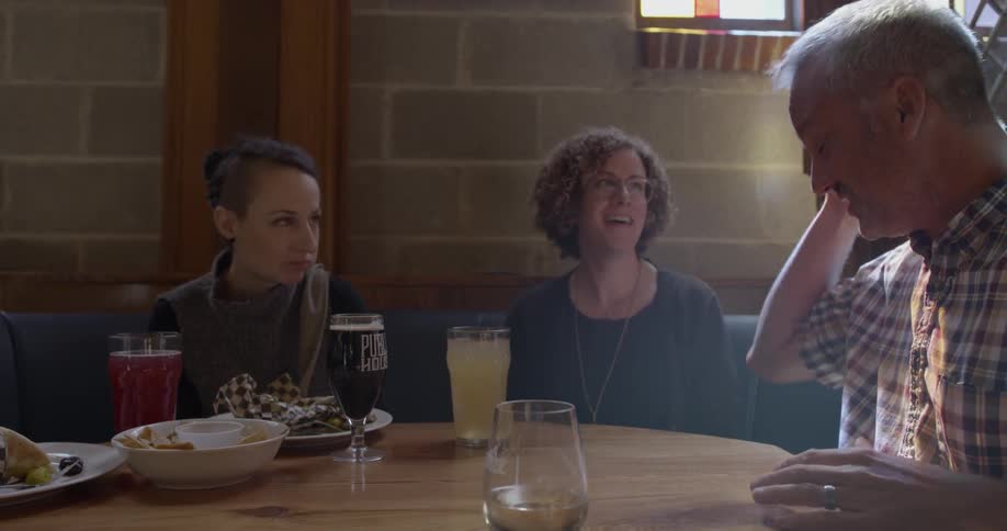 A man gestures as he tells a story to a table full of friends