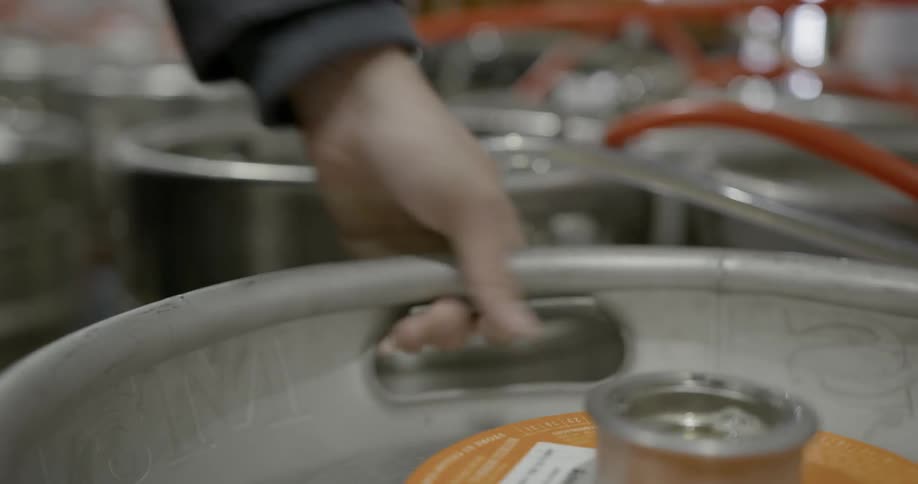 A person moves a keg into position in a row