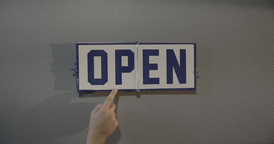 A person changes a sign from closed to open
