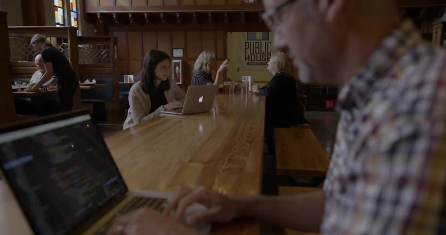 A man sitting in a diner works on his laptop
