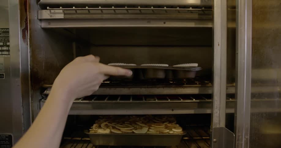 Someone is placing cupcakes into an oven