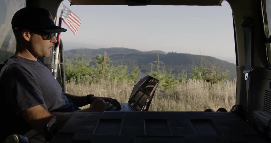 A man social distancing in his truck using a laptop