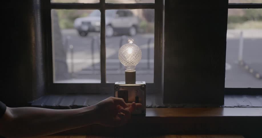 Hand flips on a switch to turn on a lamp