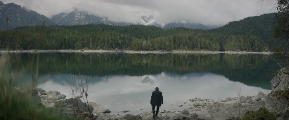 Man walks towards a mountain lake