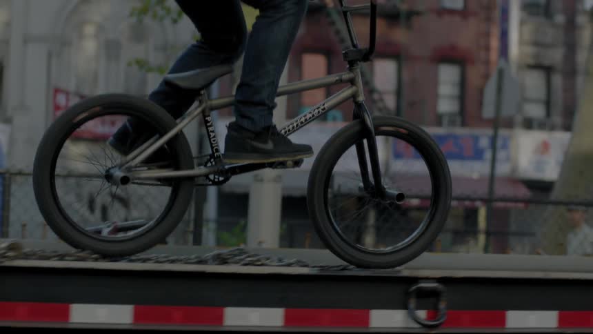 A young man is riding his bike up a trailer and then does a trick off