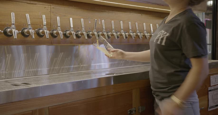 Woman pours beer into a glass in a bar