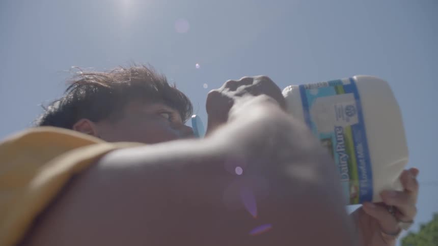 A man and woman drinking from milk jugs