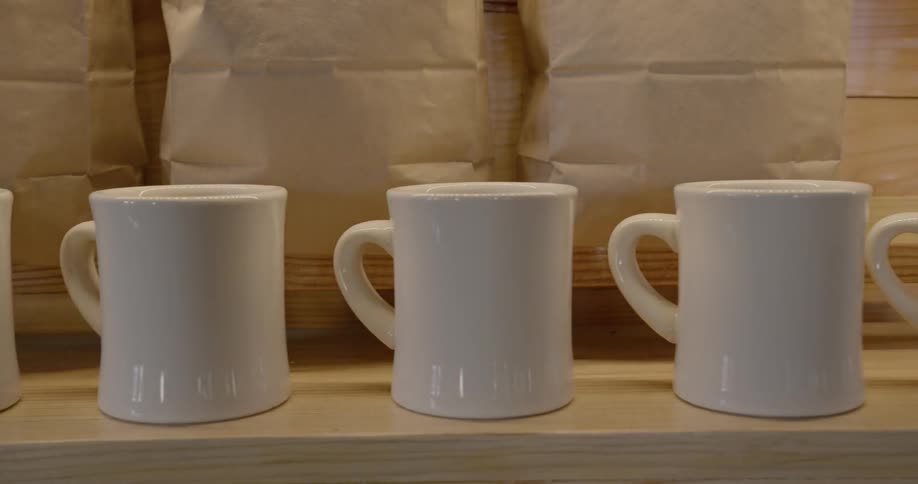 White coffee cups are lining the edge of a table