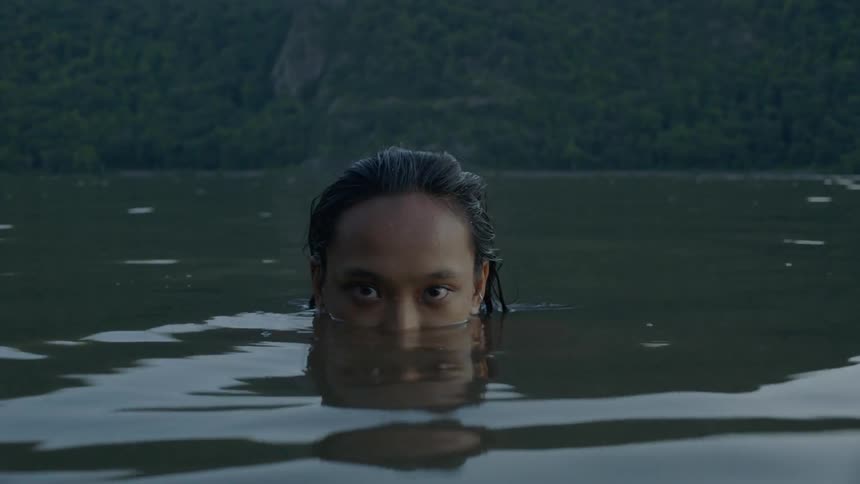 A woman stands in a lake with only the top of her face showing