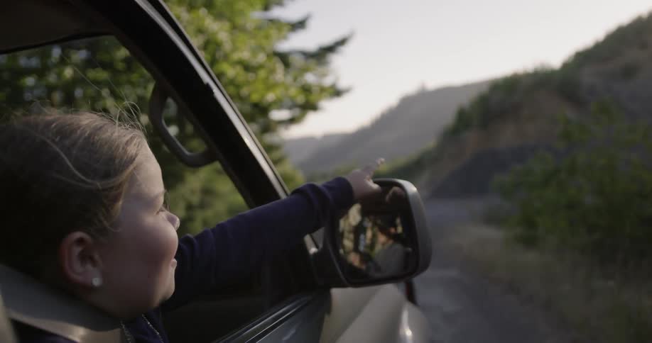 A kid points out of a window