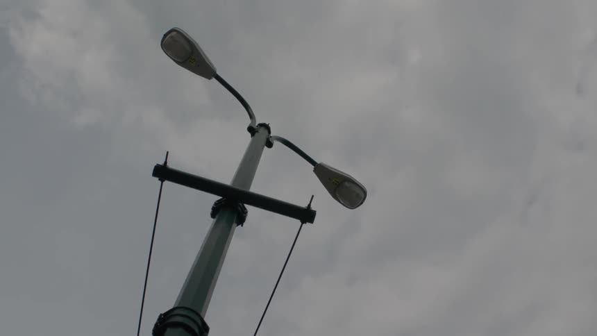 Clouds are hovering in the sky above a street lamp during the day