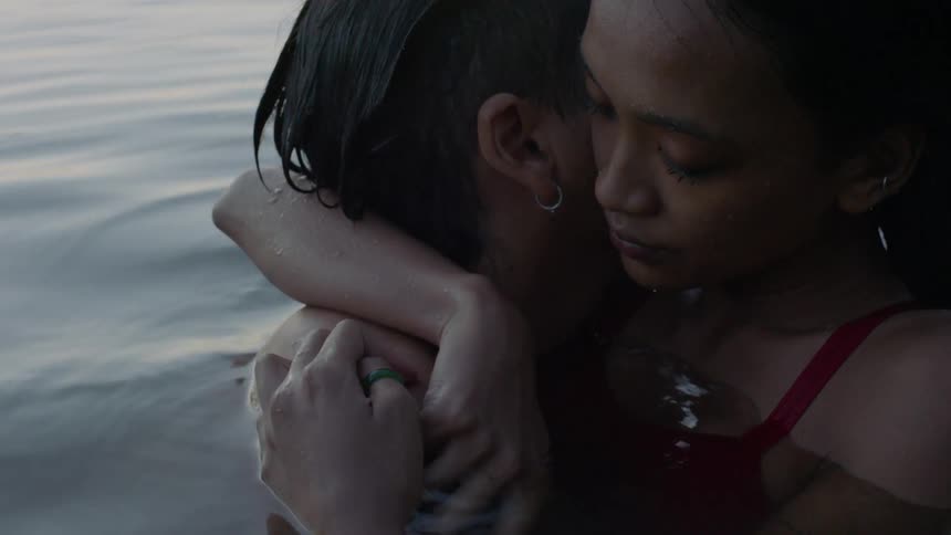 Man and woman hug while swimming in a lake
