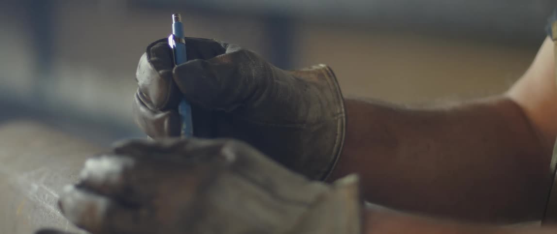 A man wearing work gloves is using a pen