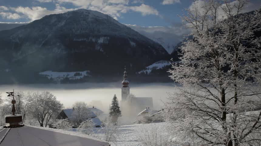 A small village covered in snow with mountains and the sky in the background