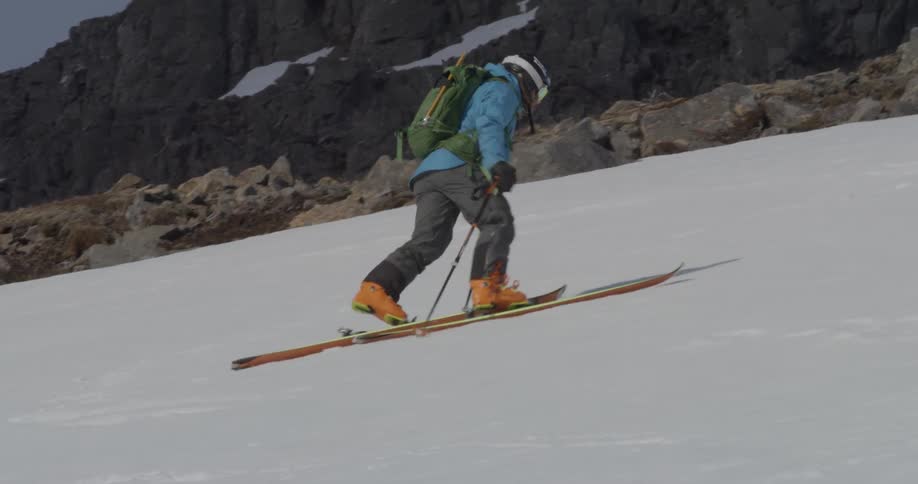 A skier climbs up a snowy mountainside