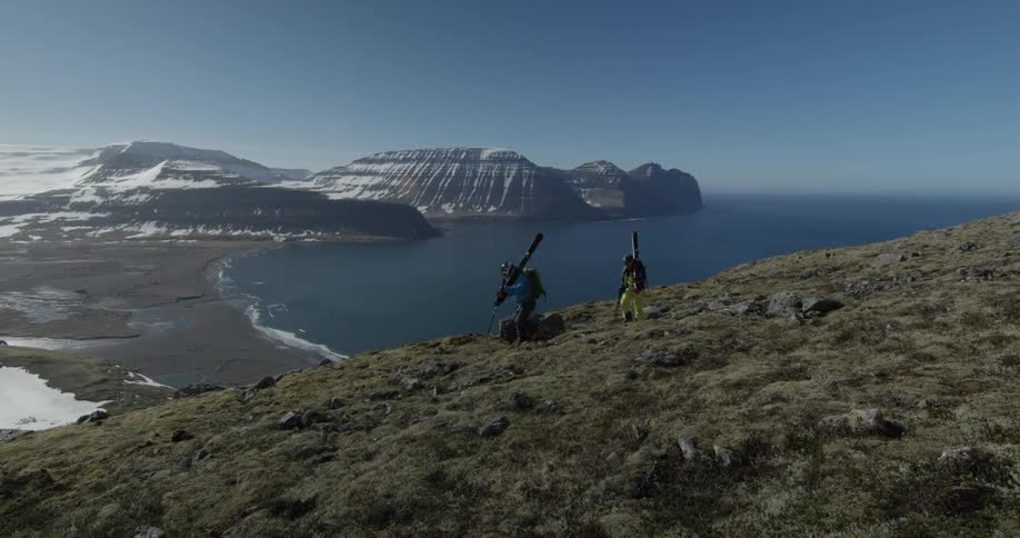 People hike in mountains with skis on their backs