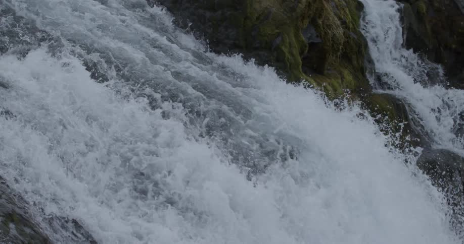Water rushes over rocks and down the waterfall