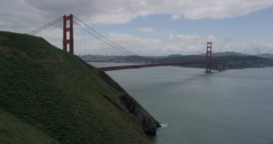 The golden gate bridge is filmed from a nearby cliff