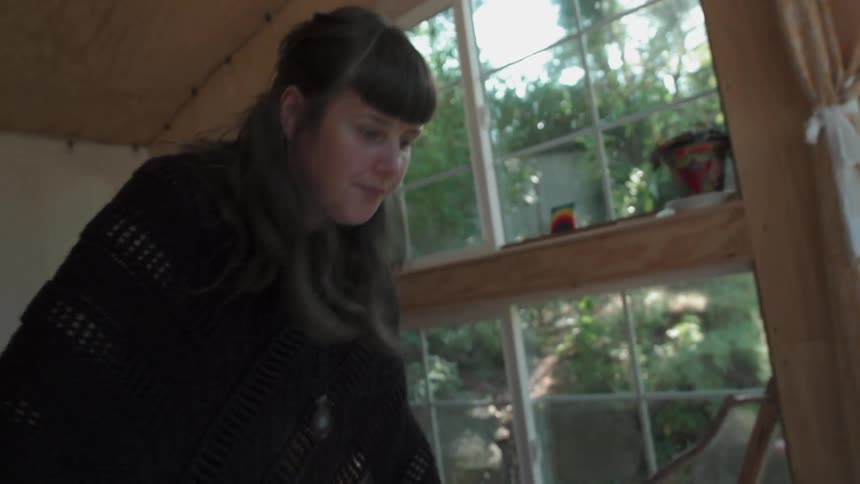 A female artist is measuring out paper in her studio during the day
