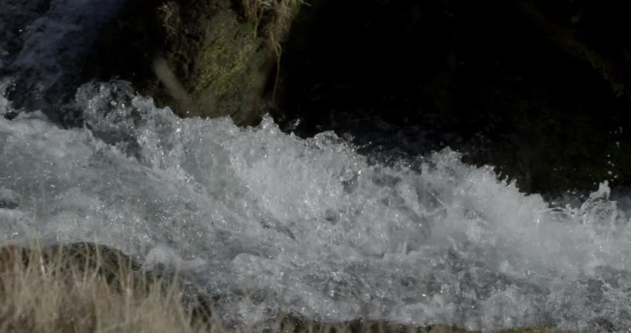 A large amount of water rapidly moving downhill and over some rocks