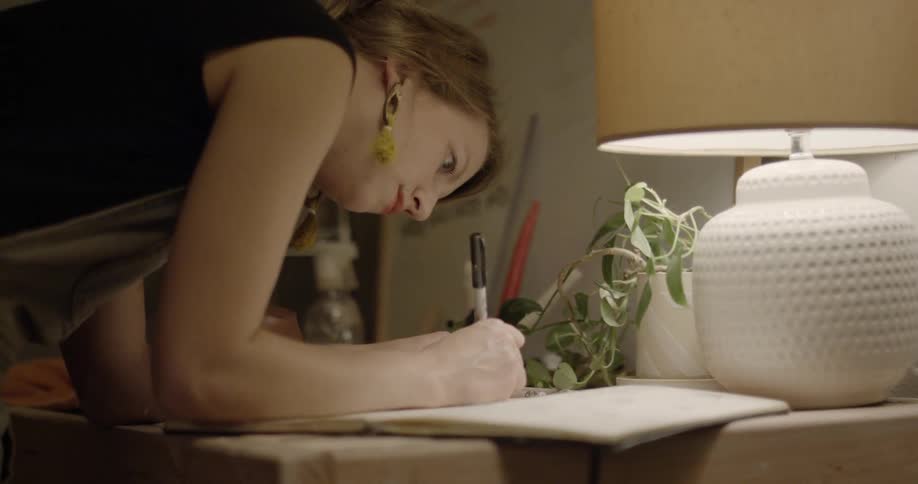 A woman is writing something down in a notebook using a marker