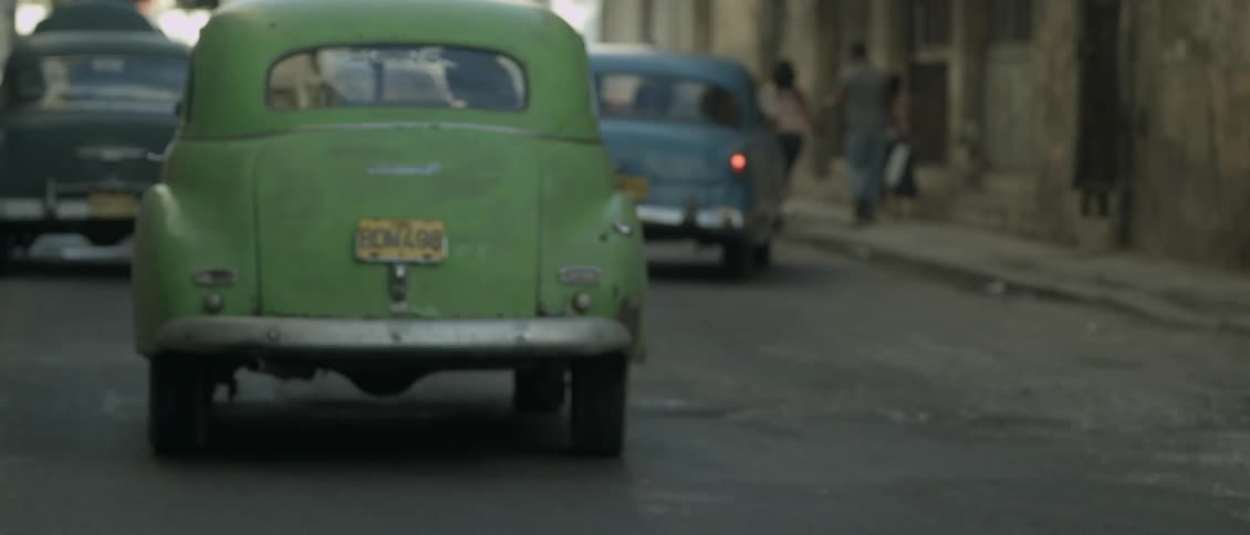 Antique cars drive on a city street