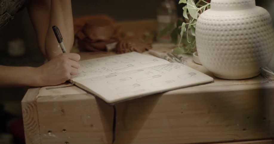 A woman is writing something down in a notebook