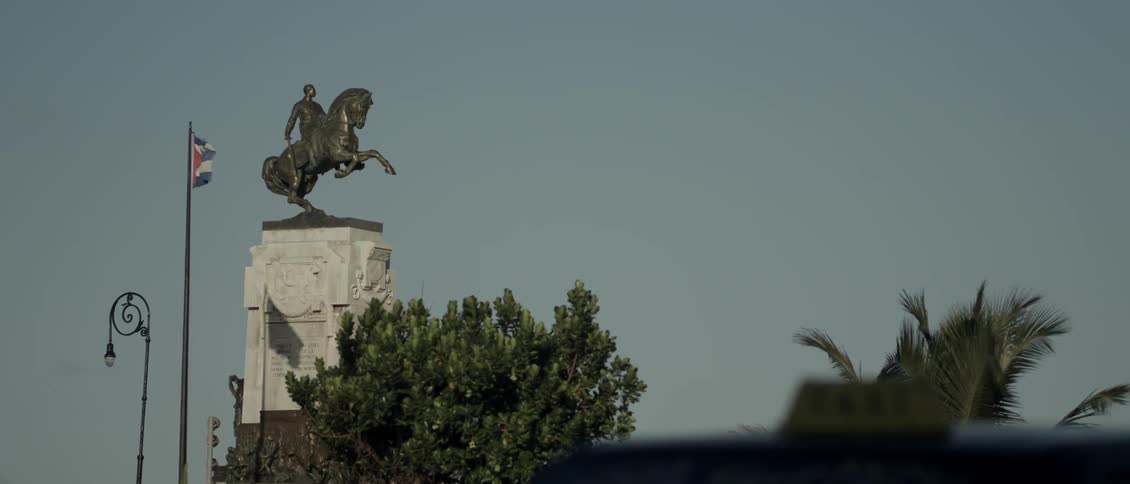 A flag flies next to a statue on a windy day
