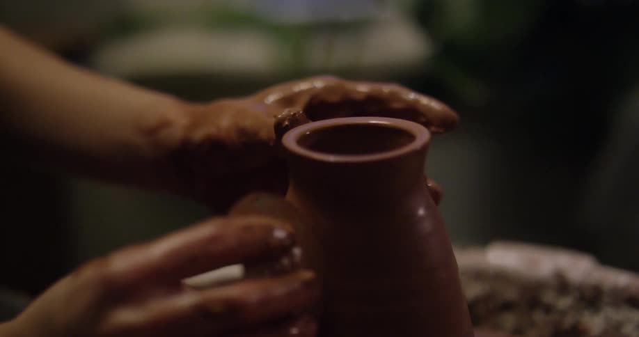 A woman is creating a clay jar
