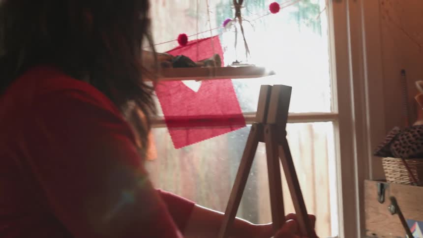A female artists is setting up an easel in a studio during the day