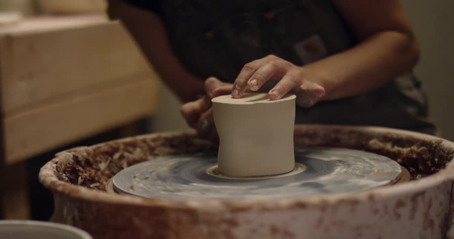 A woman is making something out of clay
