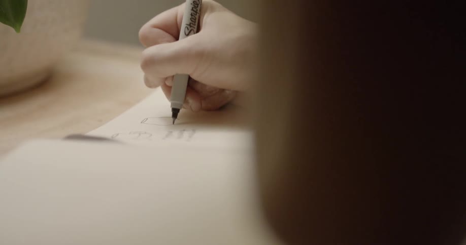 A woman draws and writes in a notebook