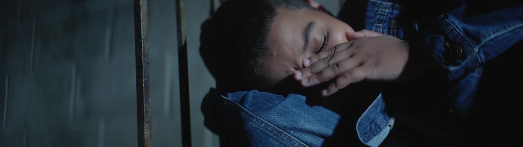 A teenage boy is crying as he sleeps outside at night