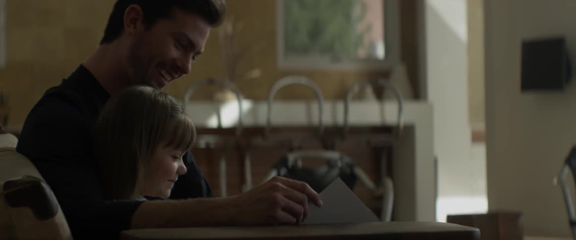 A man and child sit down and read a book