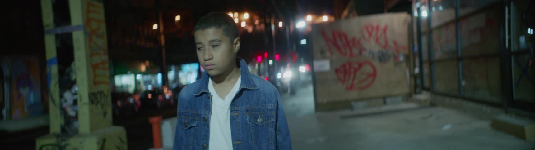 A boy walking through a city at night