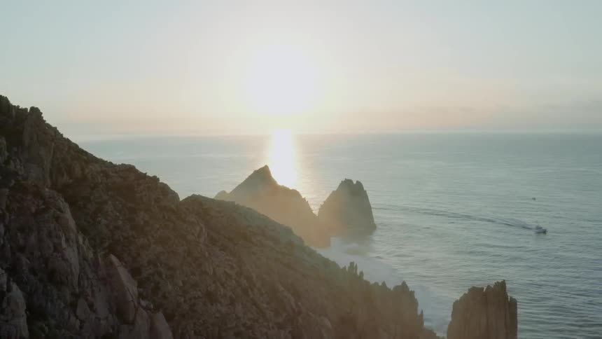 The sun sets over a coastal mountain peak
