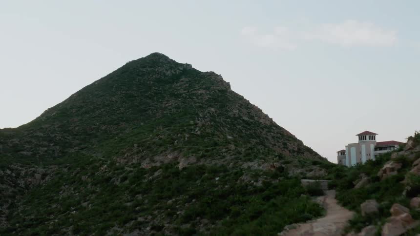 Rocky hills next to a building on a mostly clear day