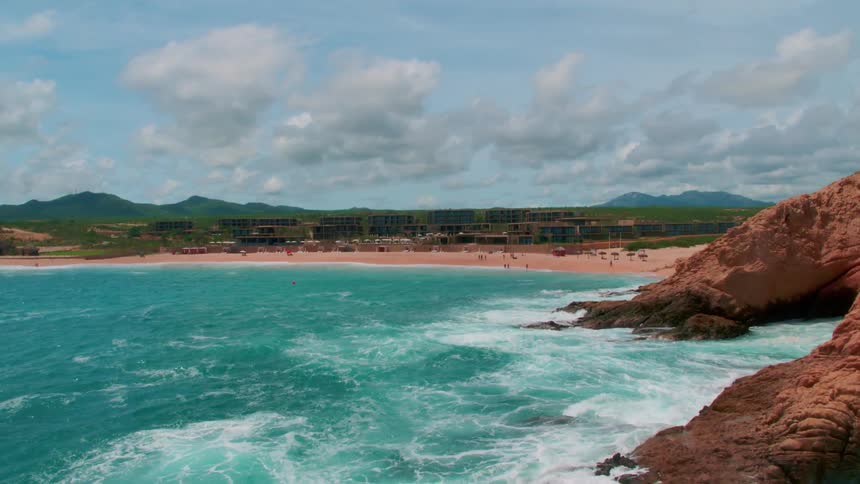 The blue water crashes against the shore