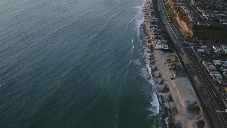 Waves rolling onto a beach near a road