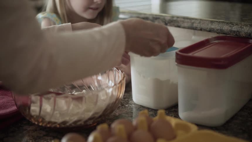 Woman and child measuring flower in the kitchen