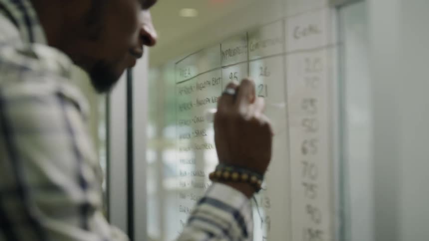 Man writes on a window with a dry erase marker
