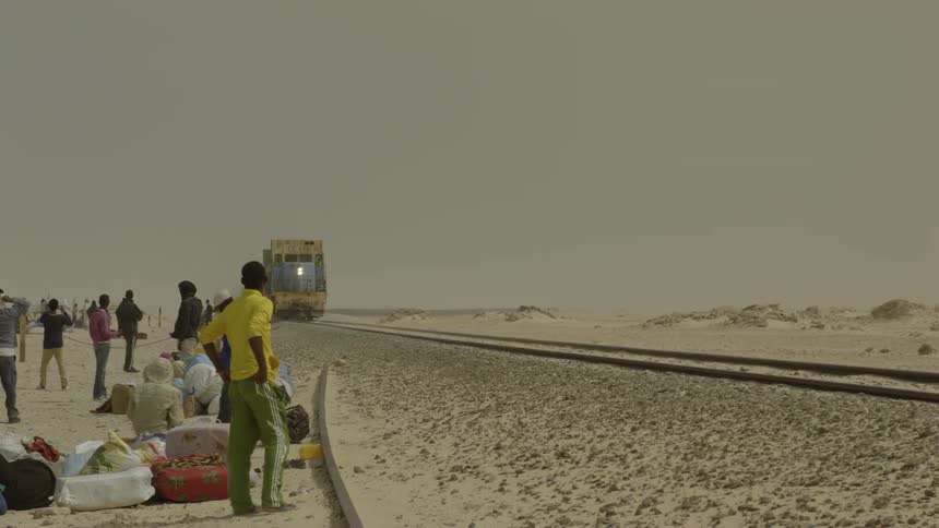 People gather in a barren as a train passes by