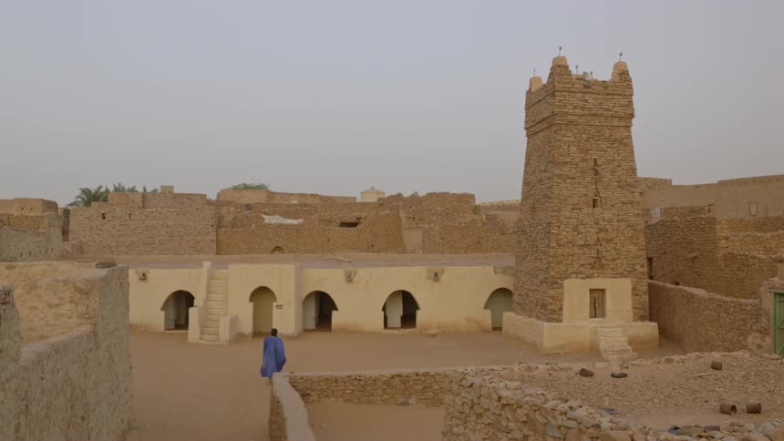 A man walks through desert buildings