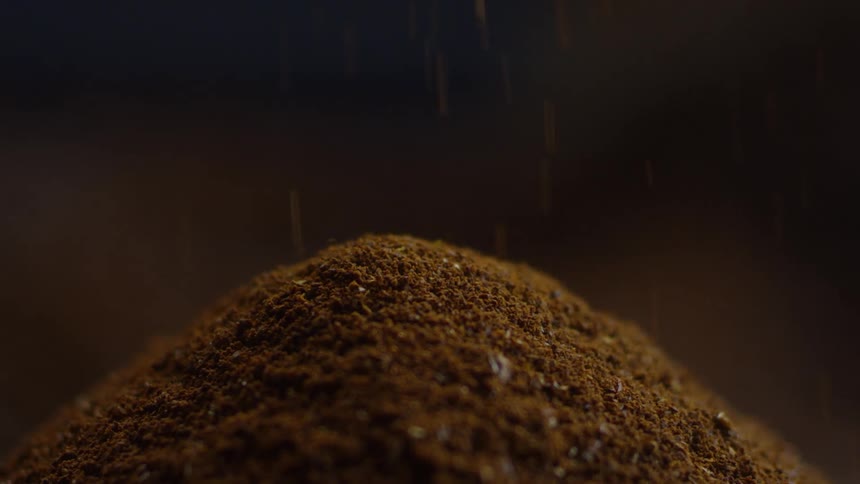 Ground coffee falling into a pile