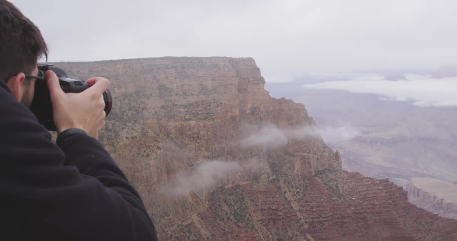 Man standing on a mountaintop takes photographs
