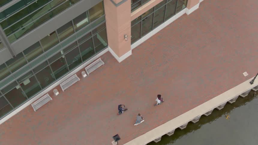 Three friends are riding scooters on a boardwalk during the day