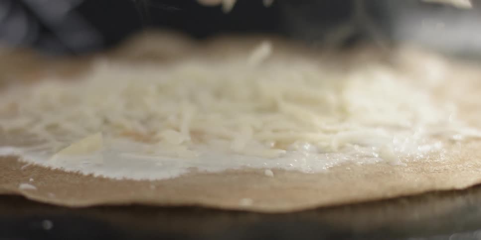 Shredded cheese is being put on top of a pizza