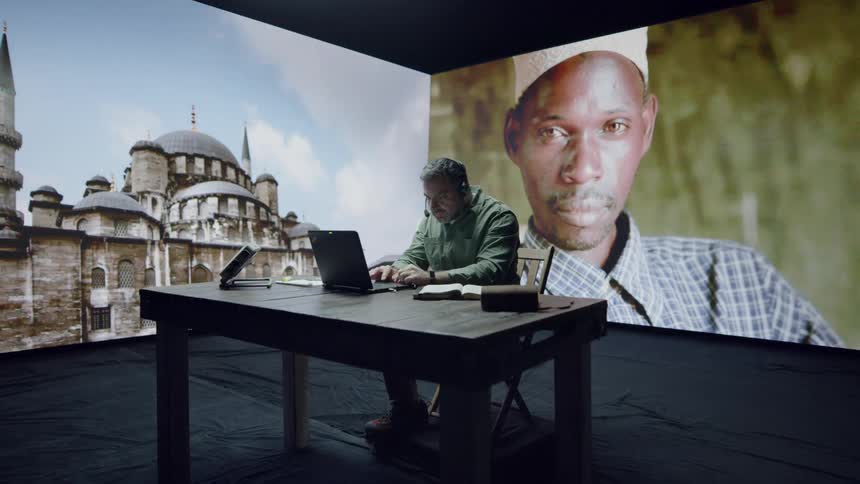 A man works on a laptop in front of LED wall